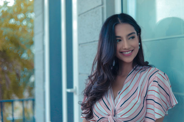 Pretty young woman standing outside a building and smiling