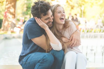 Man and woman snuggling while sitting outside by a pool