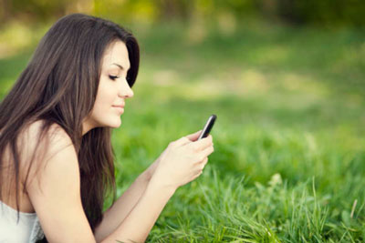 11 Proven Tinder Opening Lines You Can Send To Any Match 1 Girl lying on grass outside and checking Tinder on her mobile