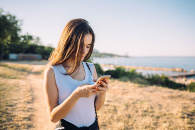 Girl standing outside and checking Tinder on her phone