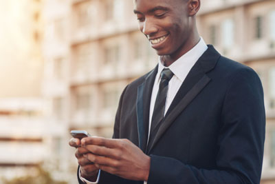 Young black man in a suit smiling at his cell phone