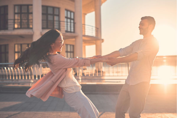 Man spinning woman around outside while they both laugh