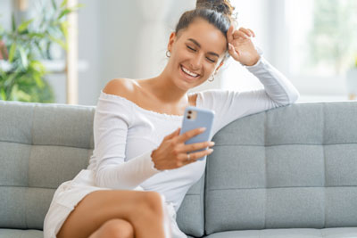 Fool-Proof Hinge Photo Tips To Boost Your Match Rate! 1 Woman smiling while looking at Hinge app