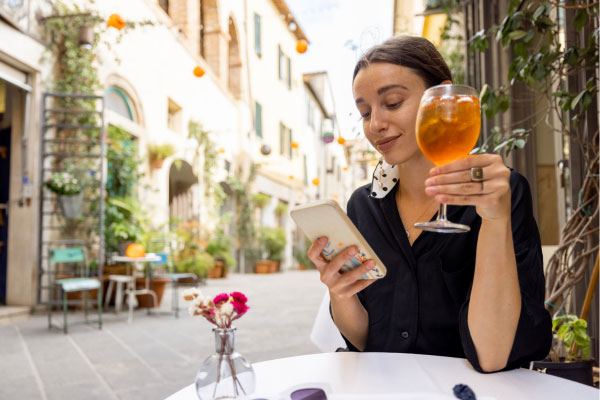 Woman drinking a glass of wine at a cafe table outdoors drinking wine