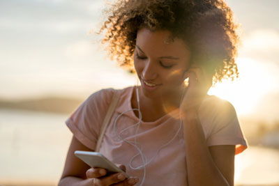 How To Get More Hinge Matches With Voice Prompts 1 Woman with earbuds listening to a voice prompt on Hinge