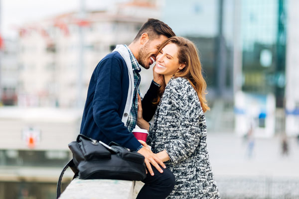 Happy couple in Boston embracing on a bridge.