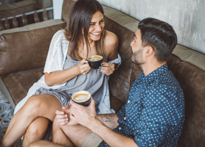 man on woman sitting on a couch drinking coffee and speed dating