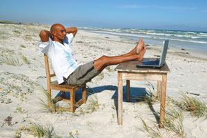 Man relaxing on beach with laptop