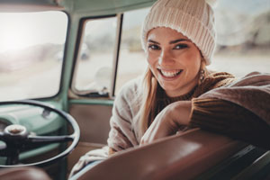 Digital nomad woman smiling from driver's seat of vehicle