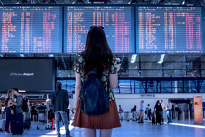 digital nomad at airport in front of departure boards