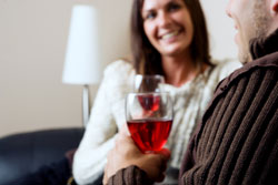 Woman smiling at the man next to her while they are enjoying a glass of wine on a first date
