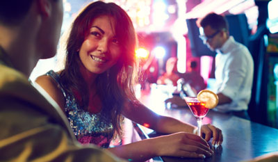 Man flirts with a woman drinking a martini at a bar